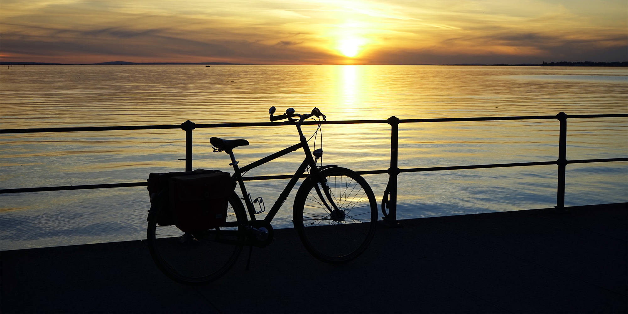 Silhouette of a bike on the beach at dusk.